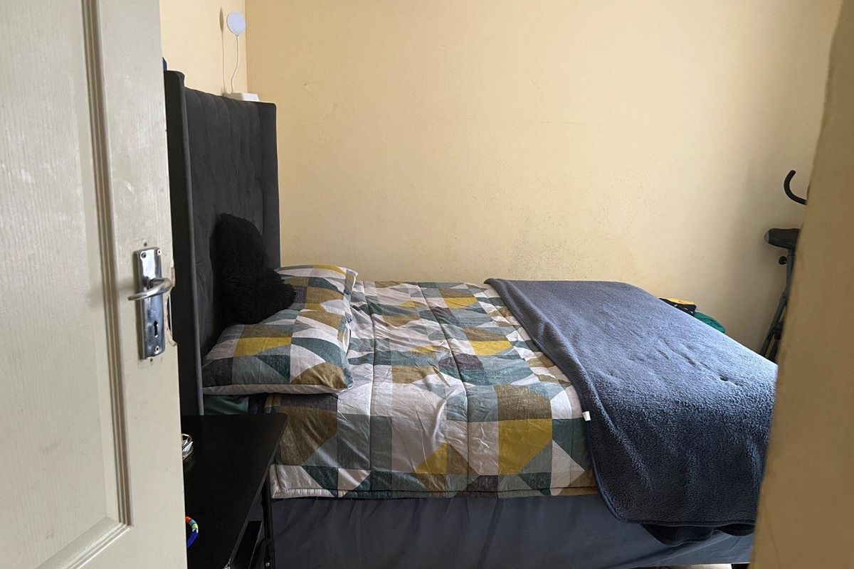A standard bedroom featuring a wall-mounted air conditioning unit and tiled flooring.