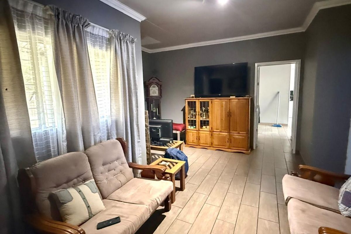 A living room featuring tiled flooring, crown molding, and track lighting, with a doorway leading to an adjacent space.