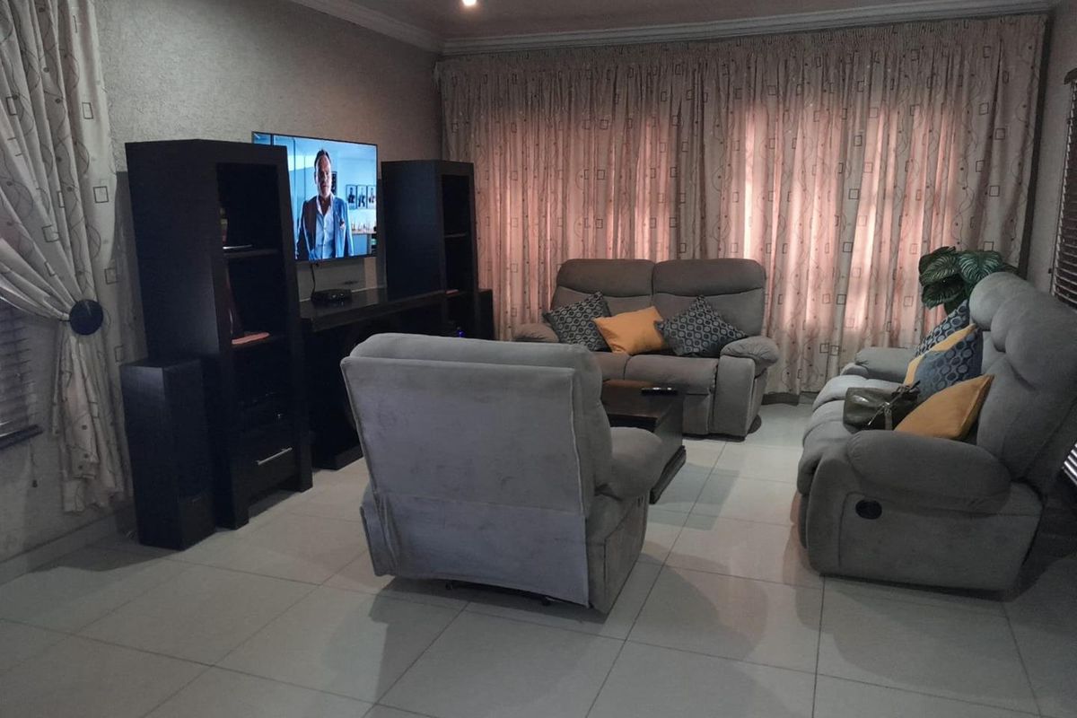 A comfortable living room featuring tiled flooring, recessed ceiling lighting, and large window treatments, providing a functional and inviting space for relaxation.