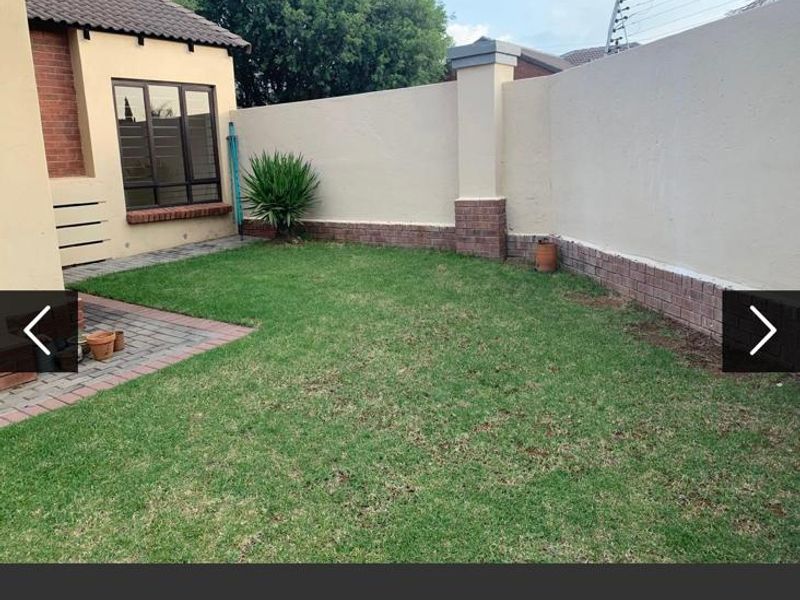 A private rear garden featuring a well-maintained lawn, brick paved area, and secure boundary wall with electric fencing.