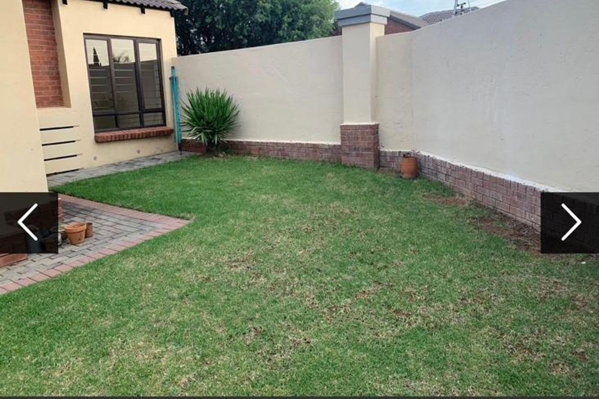 A private rear garden featuring a well-maintained lawn, brick paved area, and secure boundary wall with electric fencing.