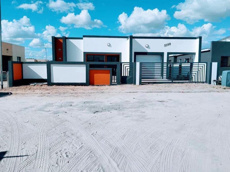 Modern single-story residential facade featuring a contemporary color scheme, secure boundary wall, sliding gate, and integrated garage access.