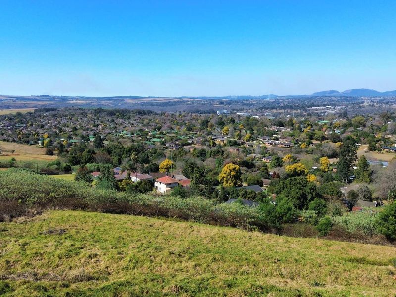 An elevated aerial view of the vacant residential land overlooking the surrounding suburban landscape and distant hills.