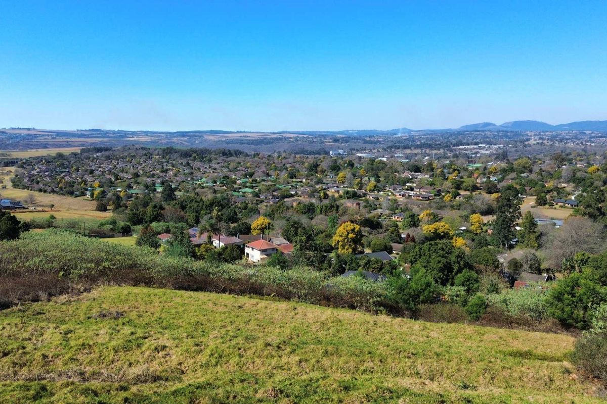 An elevated aerial view of the vacant residential land overlooking the surrounding suburban landscape and distant hills.