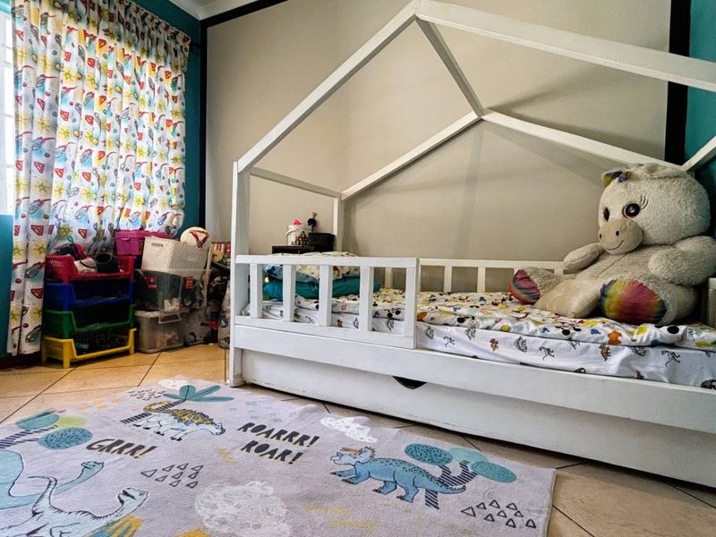A bedroom featuring tiled flooring and a window with curtains, providing a functional space for a child's room.