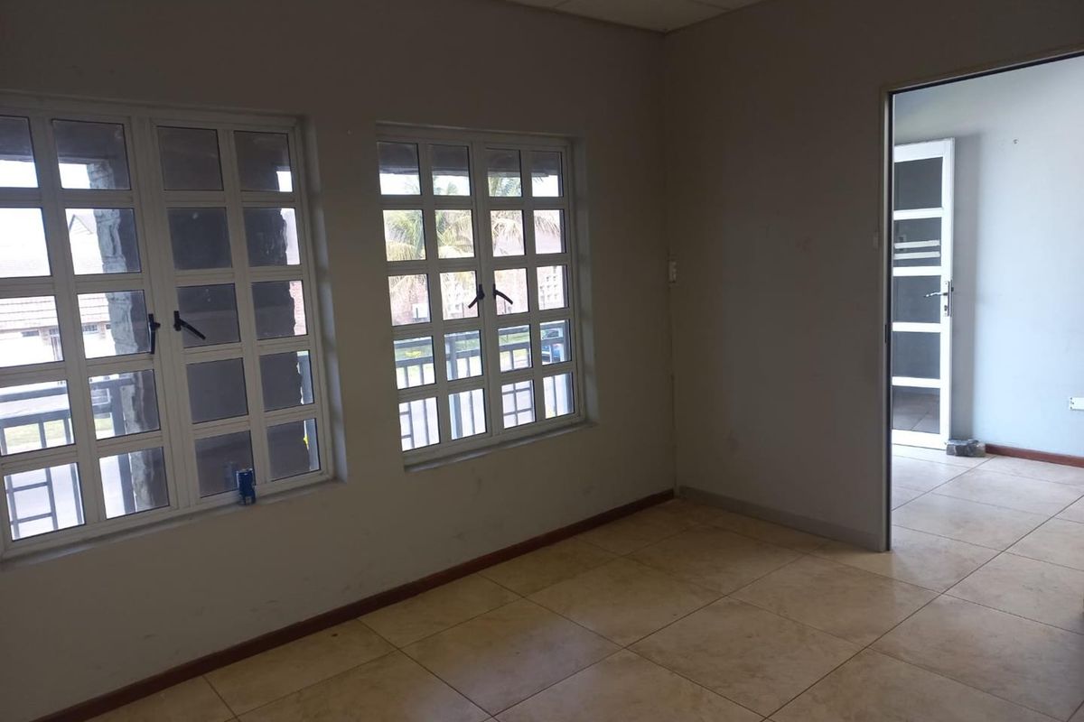 An empty office space featuring tiled flooring, grid windows, and a drop ceiling, providing a neutral environment suitable for various business configurations.