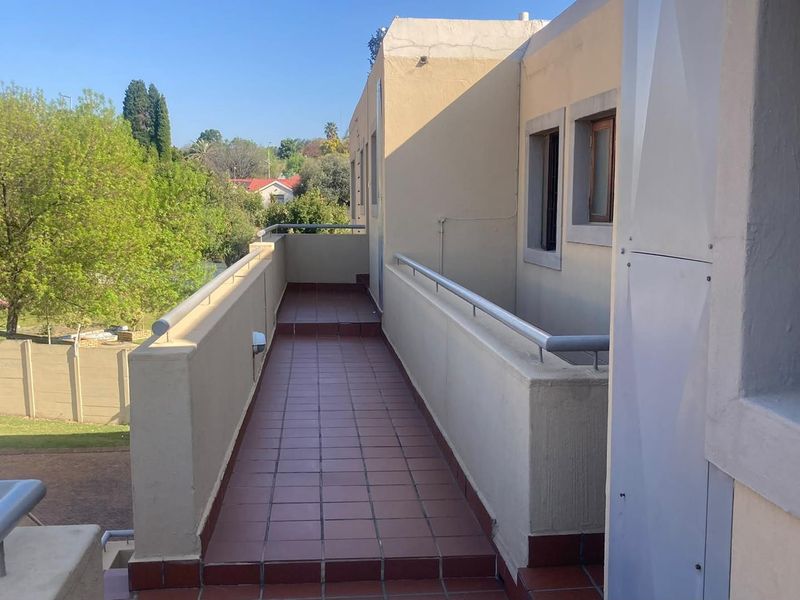 A functional outdoor balcony featuring tiled flooring and a metal safety balustrade, offering an elevated view of the surrounding greenery.