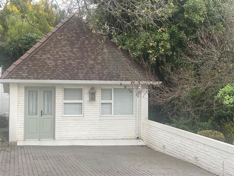 Front elevation of a cottage featuring a tiled roof, brick facade, double entrance doors, and a paved driveway area.