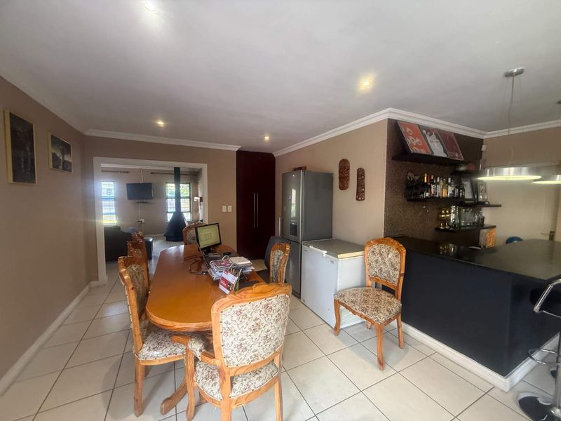 Open plan dining and bar area featuring tiled flooring, recessed lighting, and a built-in bar counter with shelving.