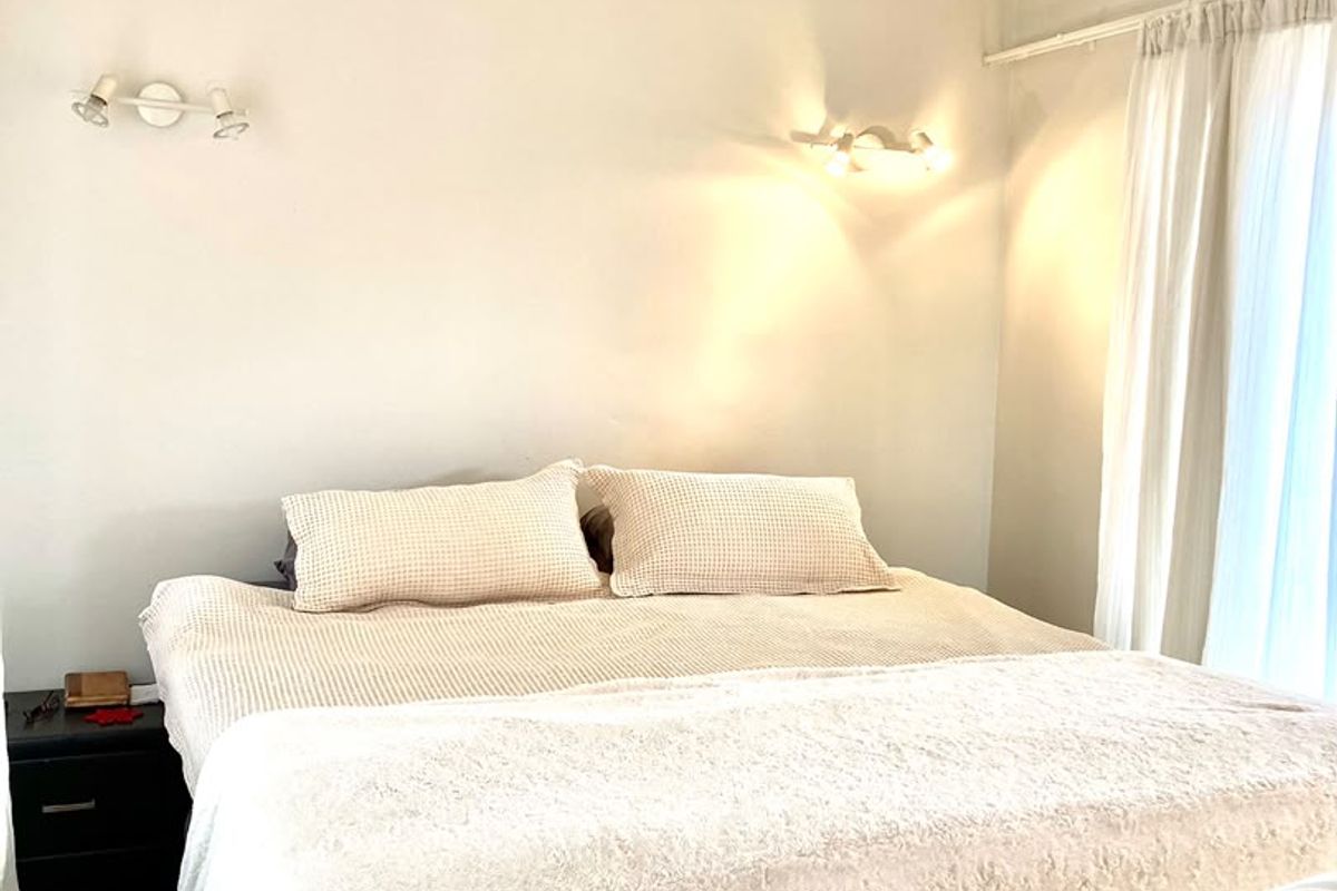 A neutrally decorated bedroom featuring wall-mounted accent lighting and window curtain tracks, providing a comfortable and functional sleeping space.