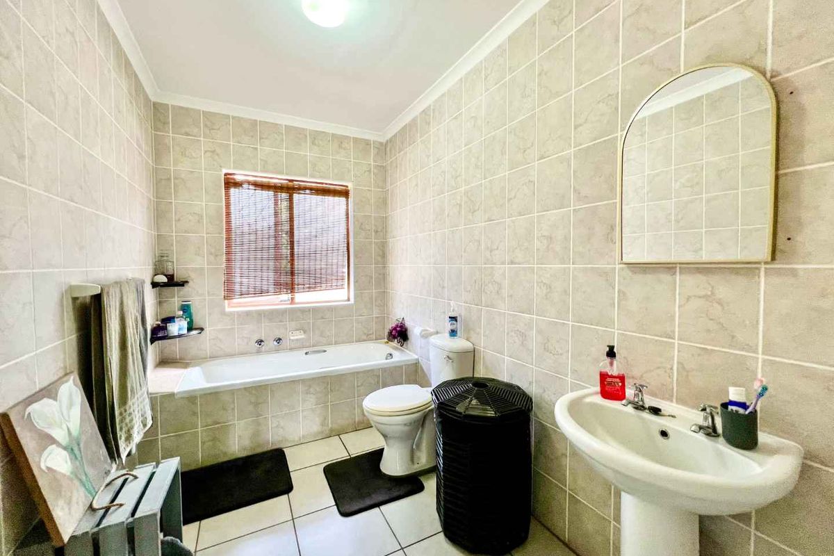 A functional bathroom featuring a built-in bathtub, pedestal sink, and floor-to-ceiling ceramic wall tiling.