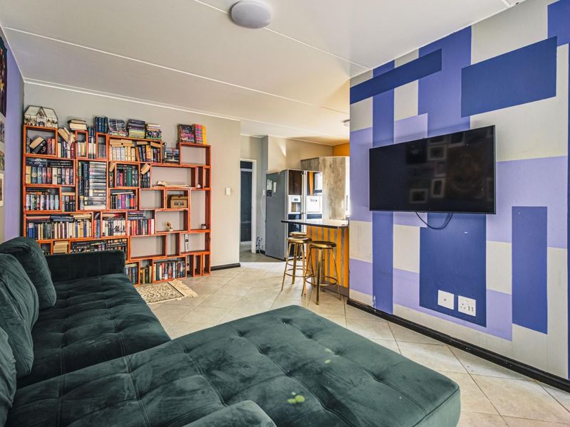 Open plan living area featuring tiled flooring and a breakfast bar, connecting to the kitchen space.