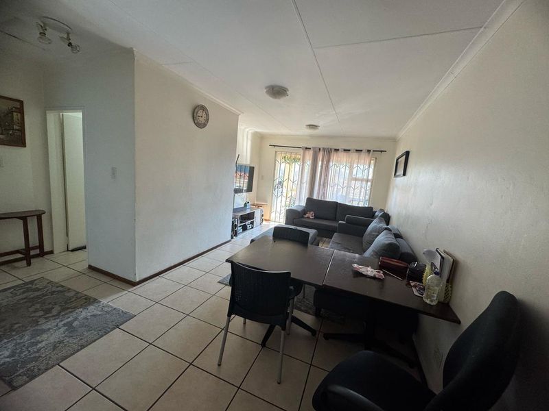 Open plan living and dining area featuring tiled flooring and a sliding door with security gate leading to the exterior.