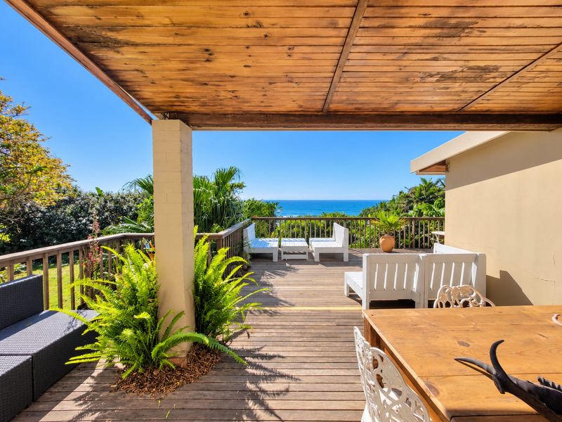 Spacious outdoor timber deck featuring a covered pergola and panoramic ocean views, providing an ideal setting for coastal entertaining.