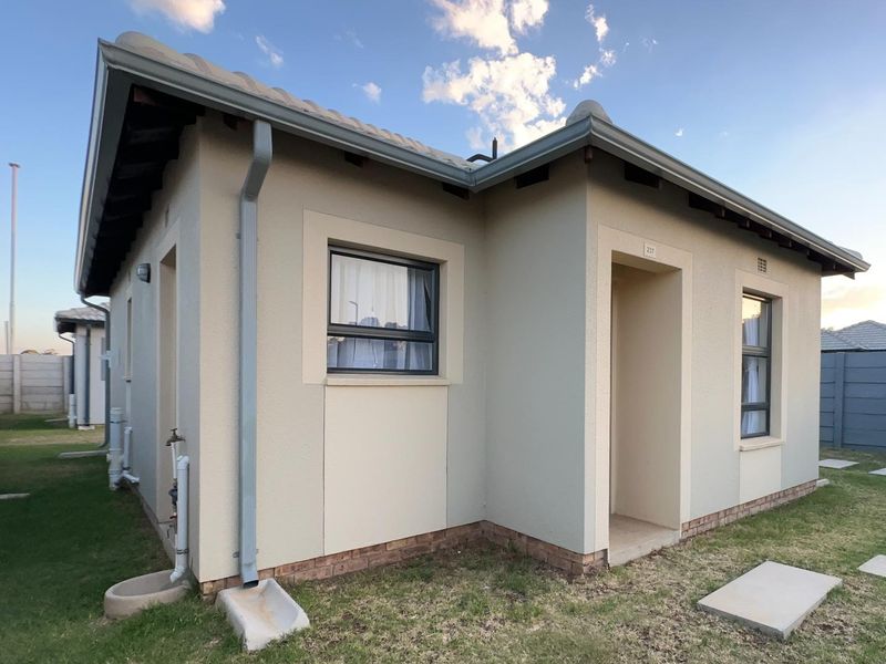 A well-maintained single-story residential house exterior featuring a tiled roof, neutral rendered walls, and modern aluminium window frames.