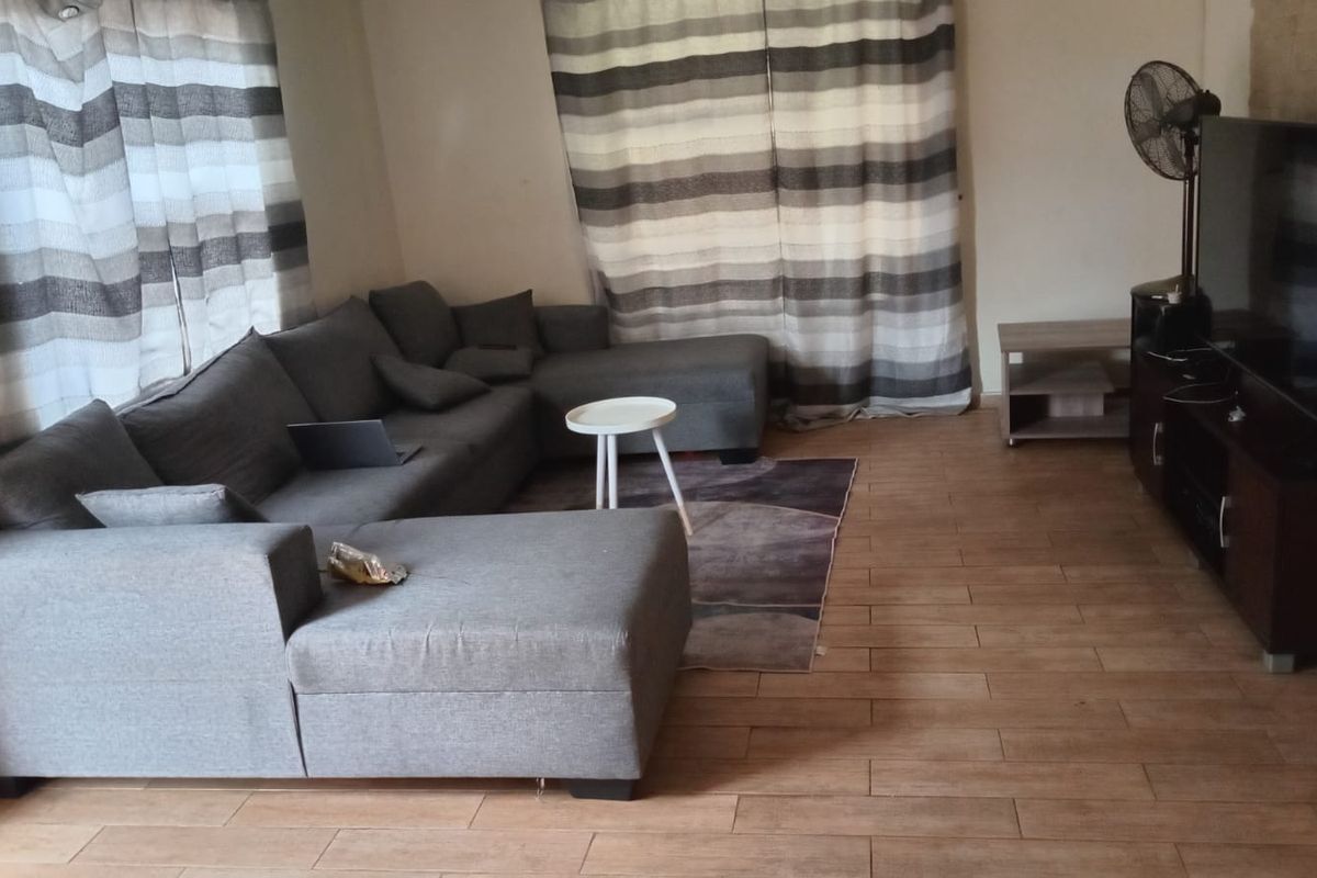 A living room featuring wood-look tile flooring and large windows with curtains.