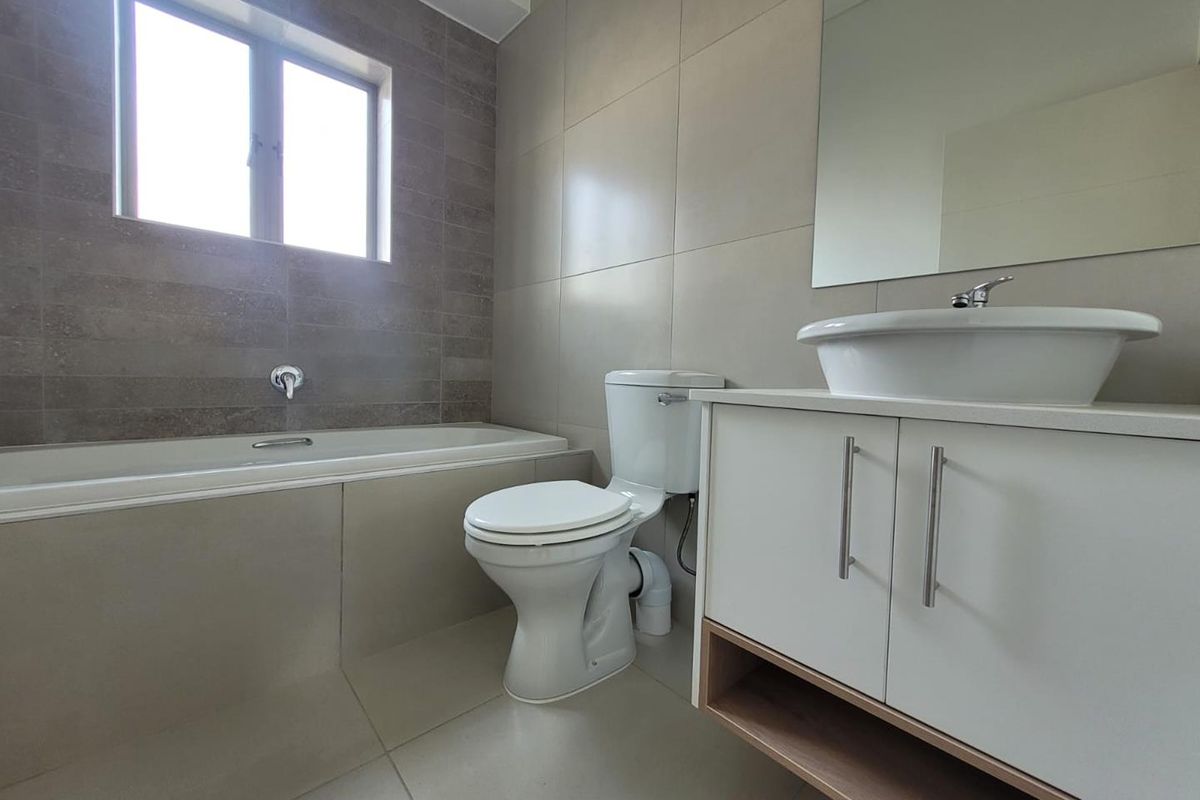 Modern bathroom featuring a built-in bathtub, a contemporary vanity with a vessel sink, and a wall-mounted mirror.