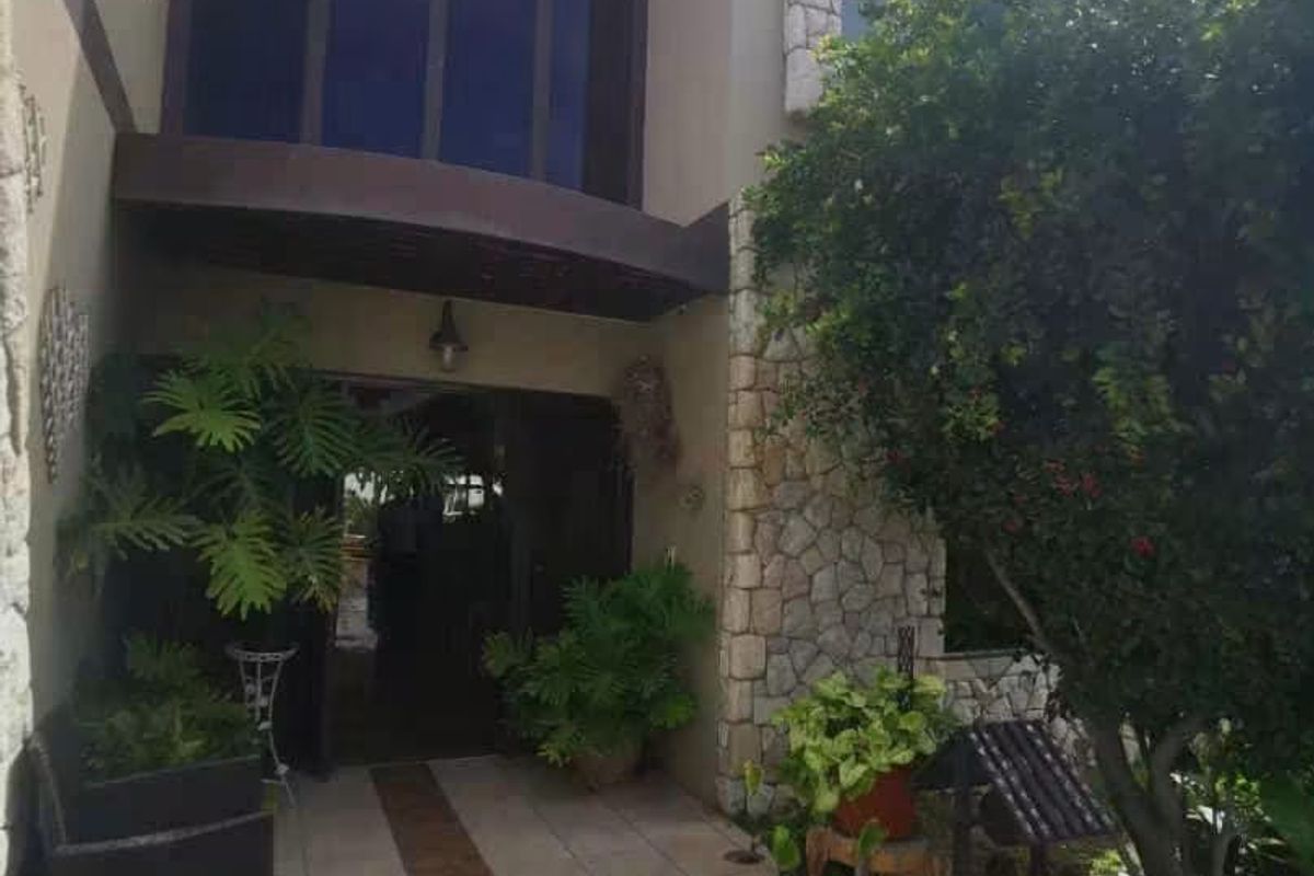 Front entrance of the house featuring stone cladding accents, a tiled walkway, and large windows under a covered entryway.