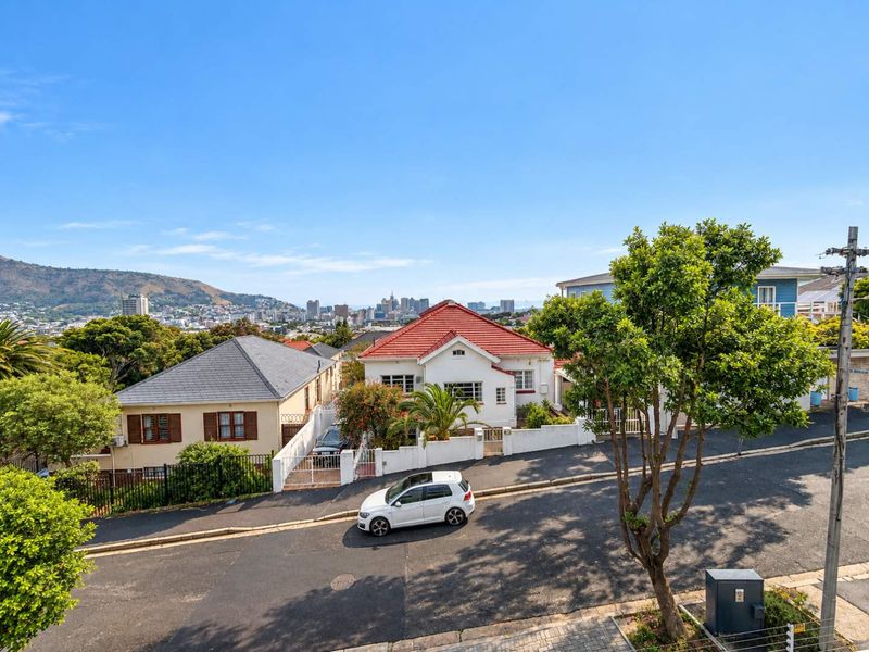An elevated street-level view of the residential neighbourhood, showcasing surrounding properties, local road infrastructure, and distant city skyline views.