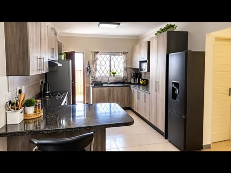 Modern kitchen featuring granite countertops, ample built-in cabinetry, tiled flooring, and a functional layout with integrated appliances.