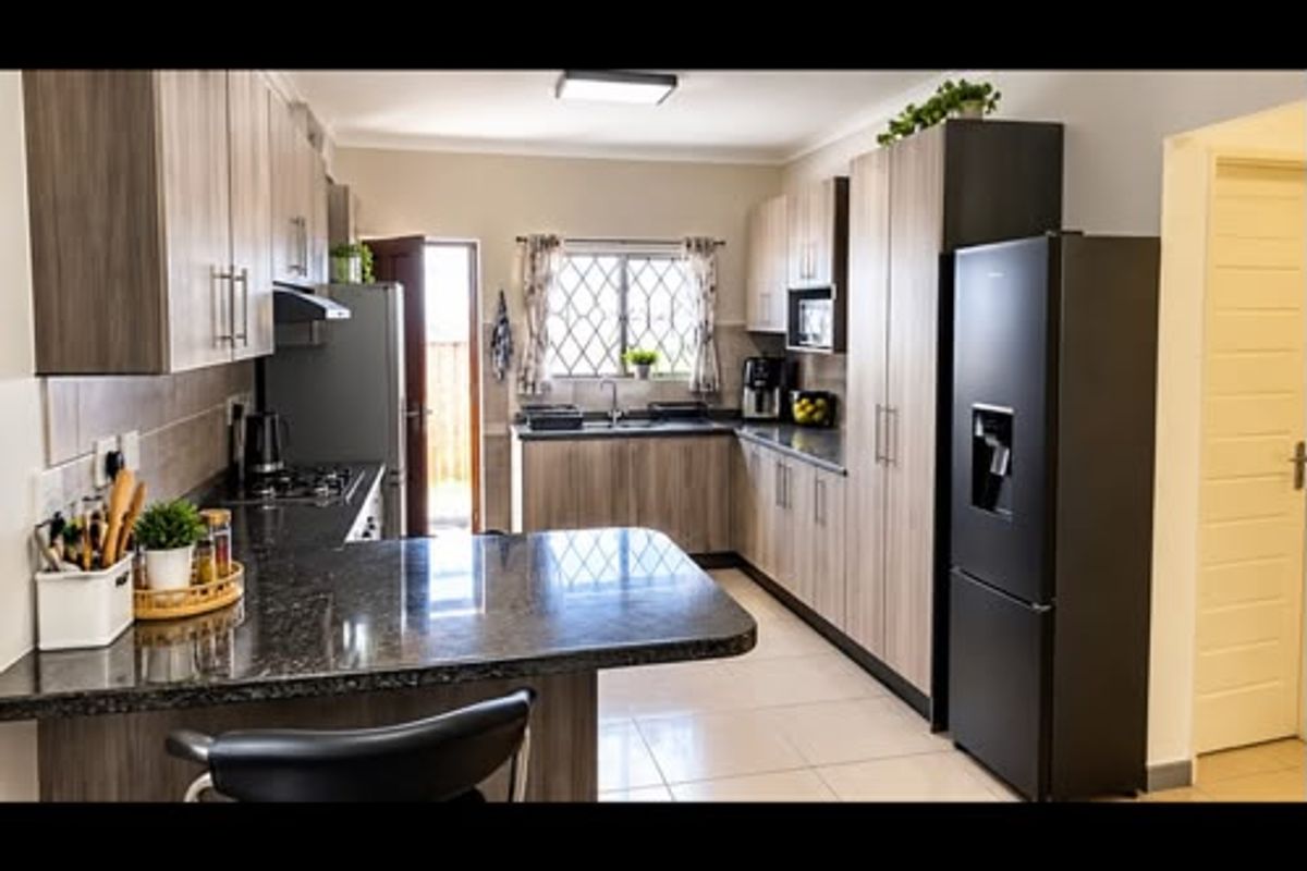 Modern kitchen featuring granite countertops, ample built-in cabinetry, tiled flooring, and a functional layout with integrated appliances.