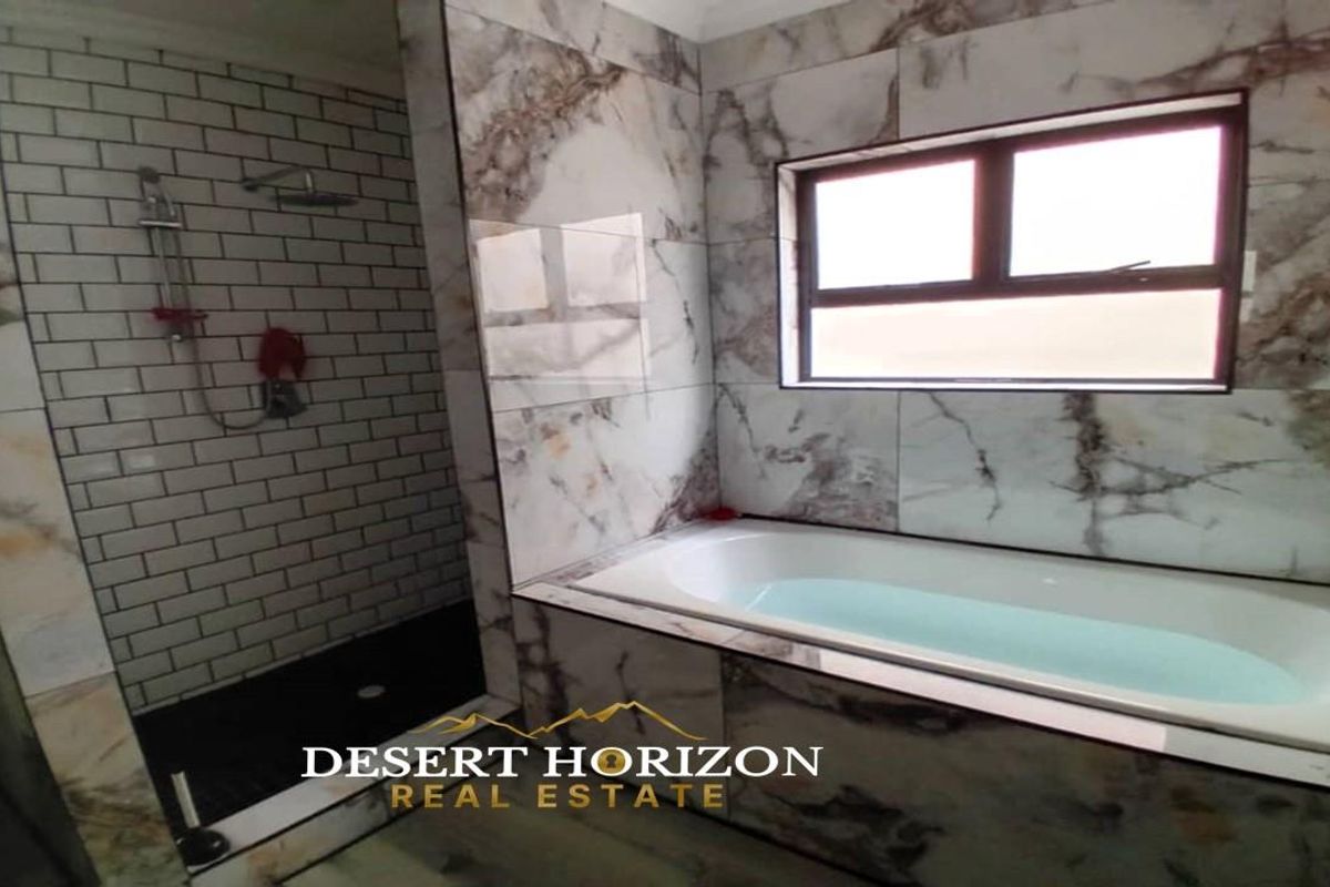 Modern bathroom featuring a tiled walk-in shower with subway tiles and a separate bathtub with marble-effect wall tiling.