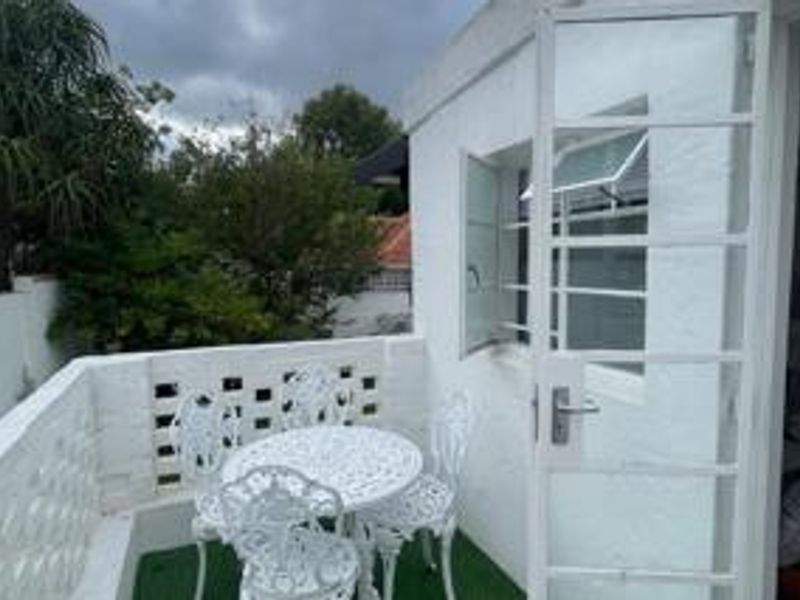 A compact outdoor patio area featuring a white brick balustrade and direct access to the interior through a security gate.