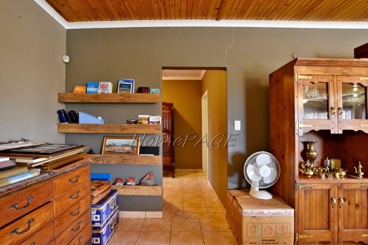Interior view of a living area featuring tiled flooring, timber-clad ceiling, and built-in wooden shelving units.