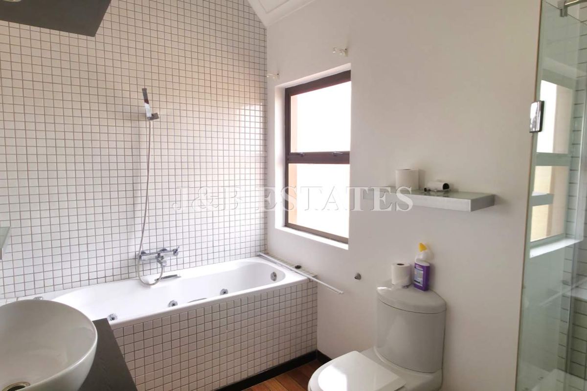 A functional bathroom featuring a built-in bathtub with tiled surround, a separate glass-enclosed shower, and a modern vessel sink vanity.