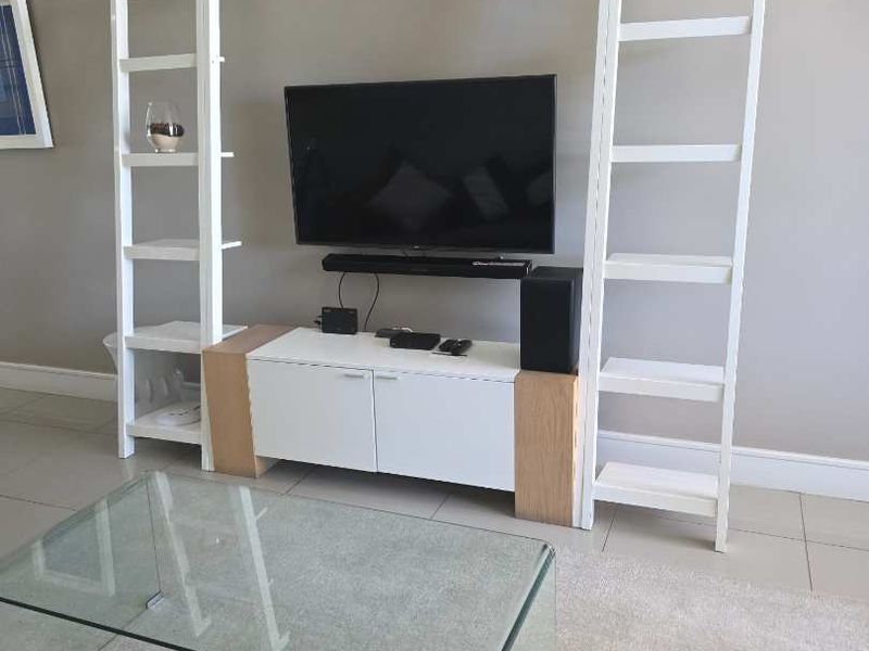 A well-maintained living room featuring neutral wall tones, tiled flooring, and clean skirting boards, providing a bright and functional space.