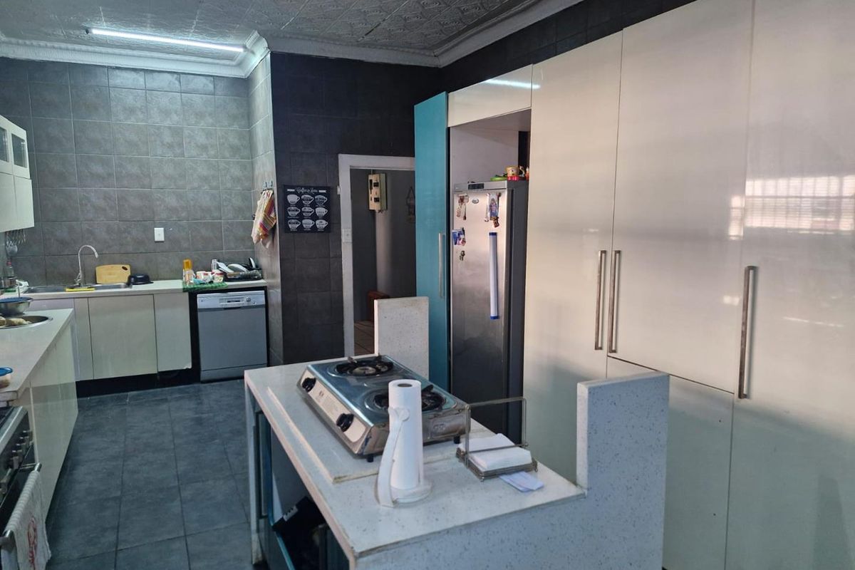 A functional kitchen featuring built-in cabinetry, a central island with a cooktop, tiled flooring, and a tiled backsplash.