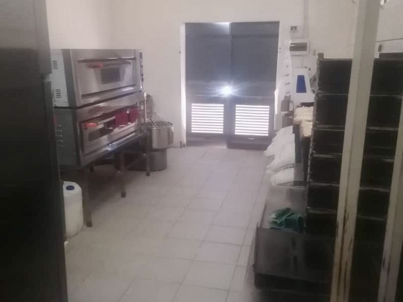A functional commercial kitchen space featuring stainless steel ovens, tiled flooring, and industrial lighting, suitable for professional food preparation.