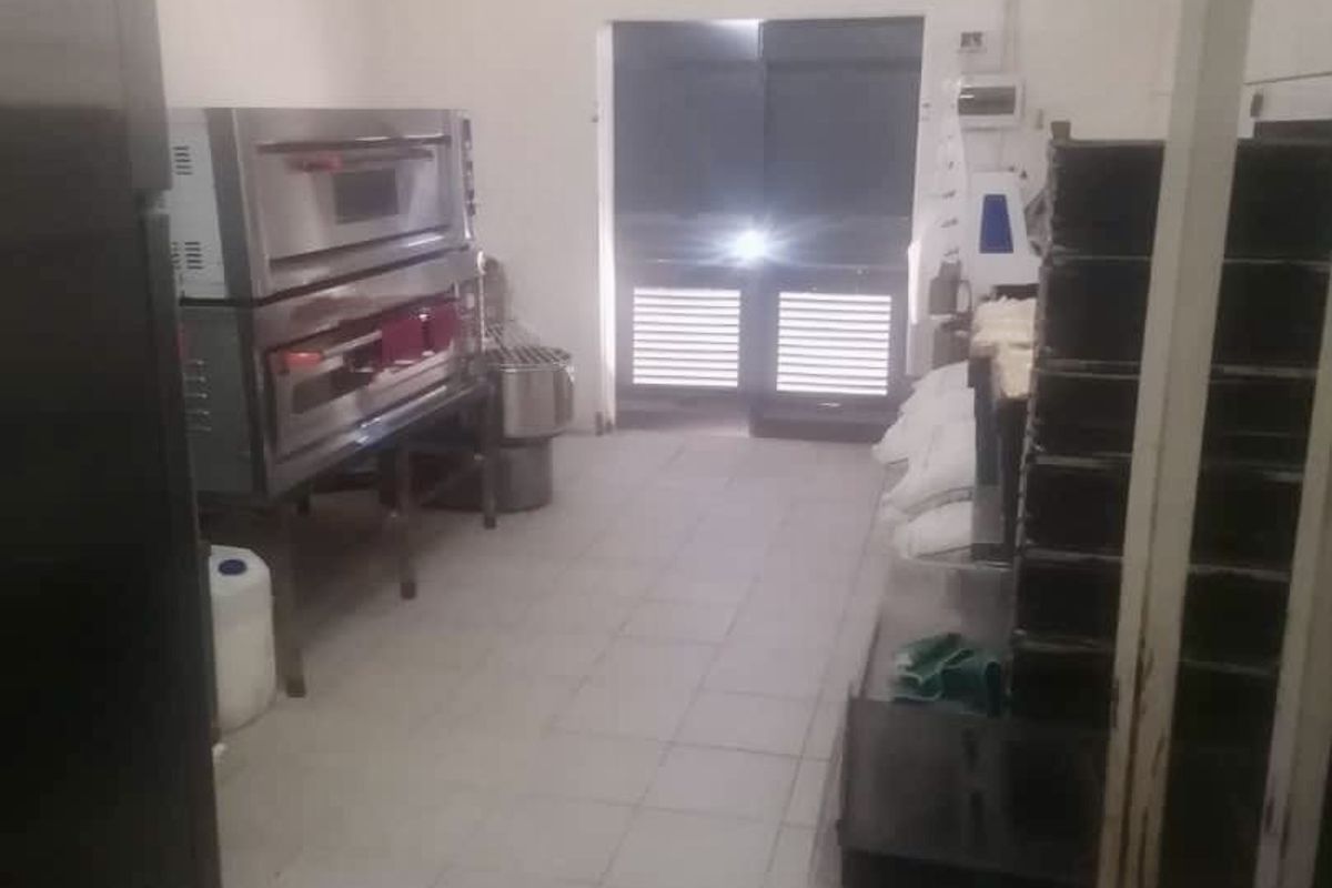 A functional commercial kitchen space featuring stainless steel ovens, tiled flooring, and industrial lighting, suitable for professional food preparation.