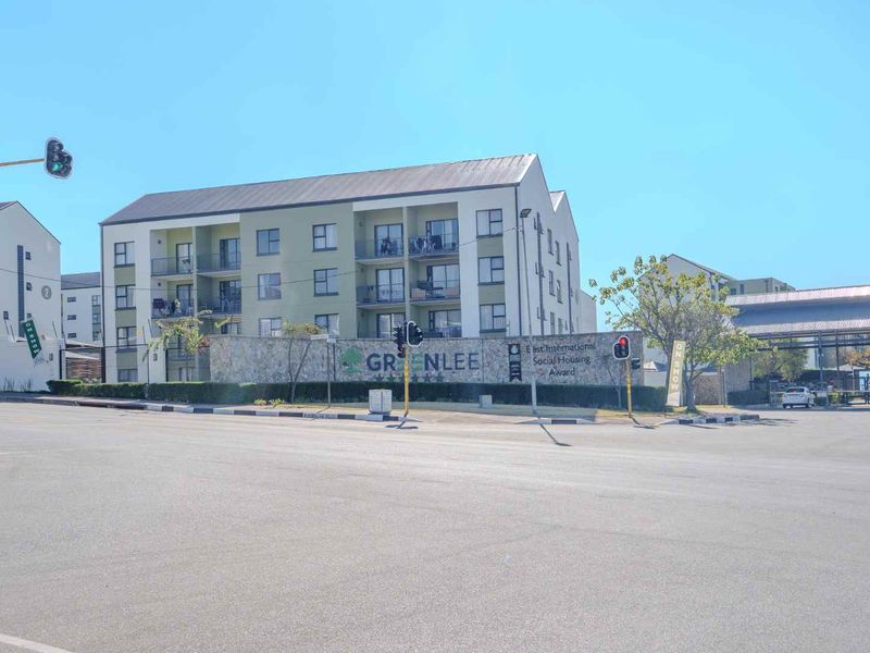 Street view of the Greenlee apartment complex, featuring modern multi-story residential buildings with balconies and a prominent stone-clad entrance wall.
