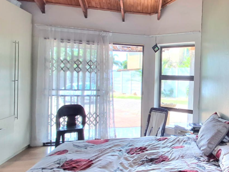 Bedroom featuring a high exposed timber rafter ceiling, built-in wardrobe, and direct access to the exterior through a sliding door with a security gate.