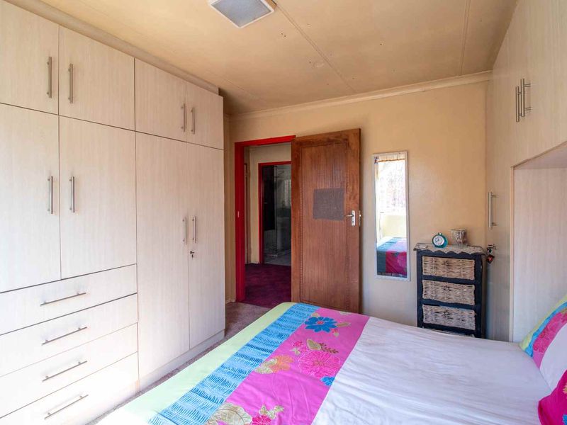 A bedroom featuring extensive built-in cabinetry and storage, providing functional space with direct access to an adjoining room.