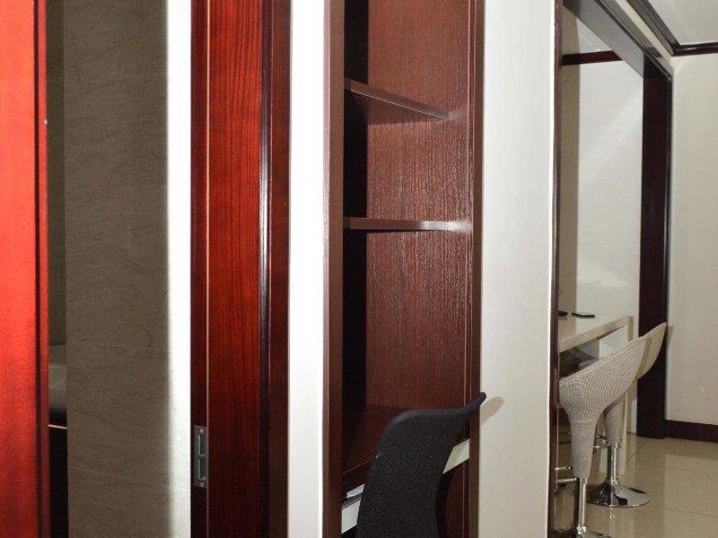A well-maintained hallway featuring built-in timber shelving and a dedicated desk area with tiled flooring and dark wood trim.
