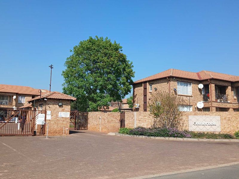 Front entrance view of the apartment complex featuring face brick architecture, secure gated access, and paved driveway.