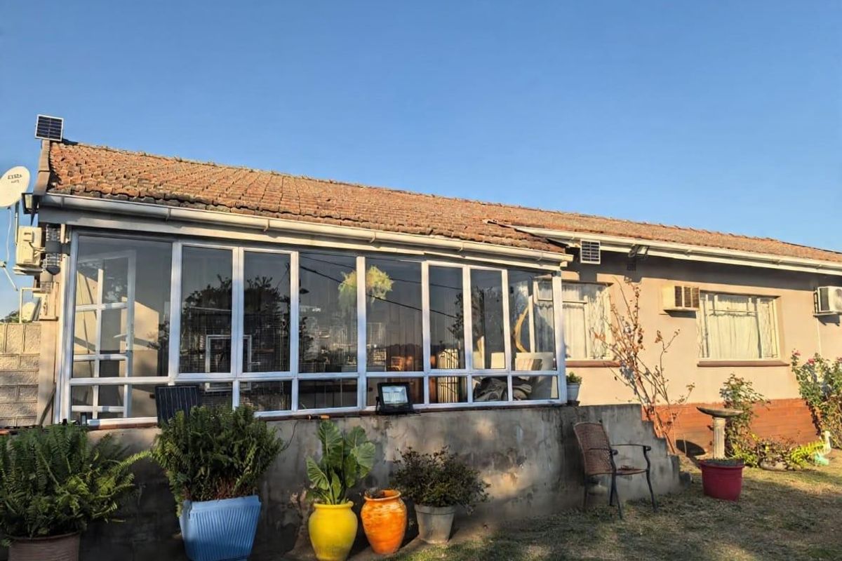 Rear elevation of the house featuring an enclosed sunroom, terracotta tiled roof, and established garden area.