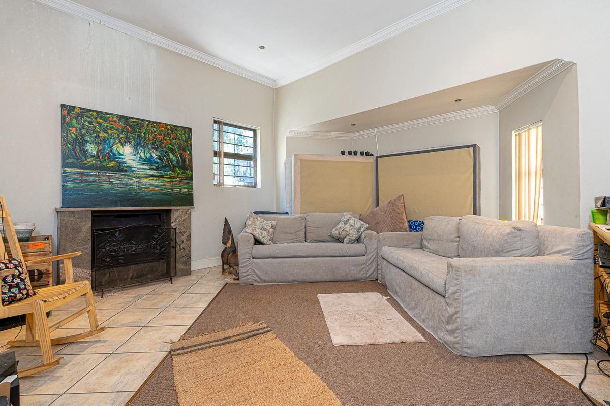 A living room featuring a built-in fireplace with stone surround, crown molding, and tiled flooring, offering a spacious layout for family living.