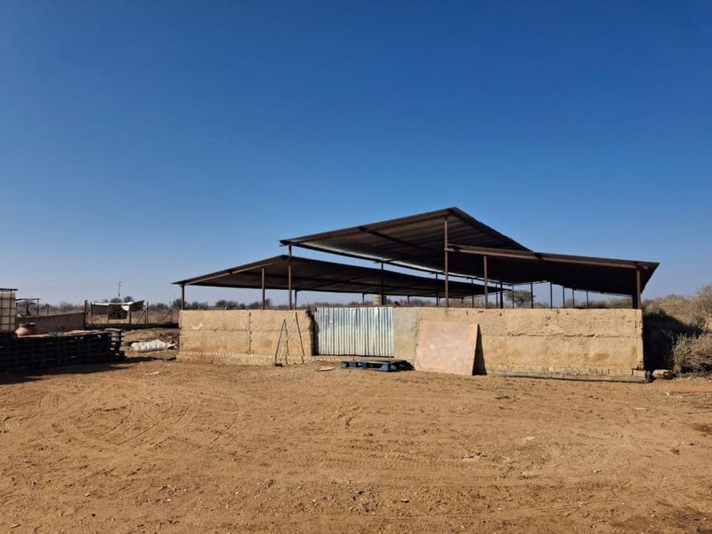 An outdoor utility structure featuring a corrugated metal roof and mud brick walls, suitable for agricultural or storage use on a small holding.