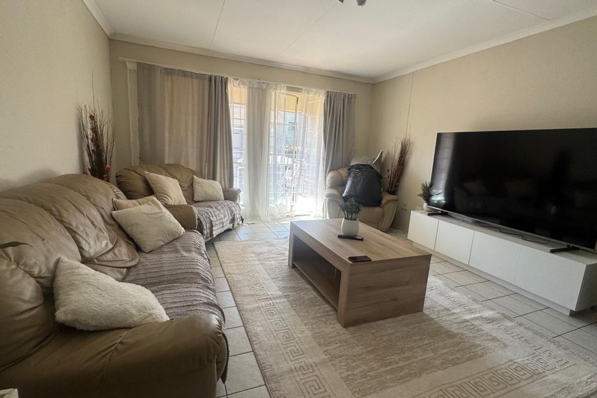A comfortable living room featuring tiled flooring and a sliding glass door that provides access to the outdoor area.