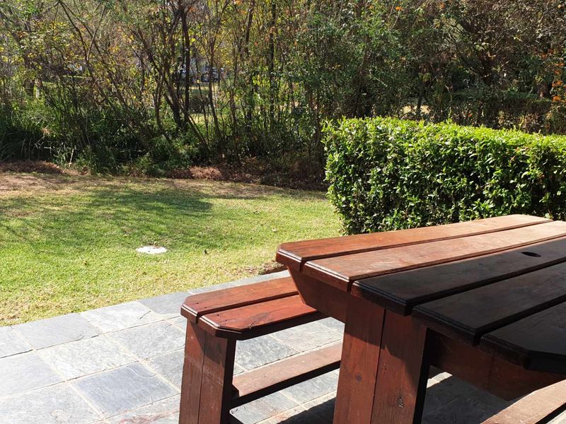 A paved outdoor patio area overlooking a private garden with established greenery and hedging.