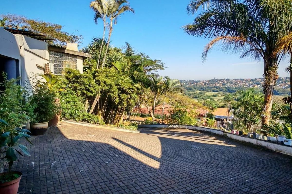 A paved rear courtyard area featuring a glass block window and expansive views over the surrounding landscape.