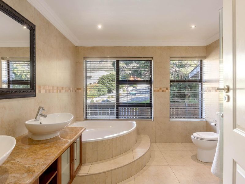 A well-appointed bathroom featuring a dual vanity with stone countertop, vessel sinks, and a raised corner bathtub set against large windows.