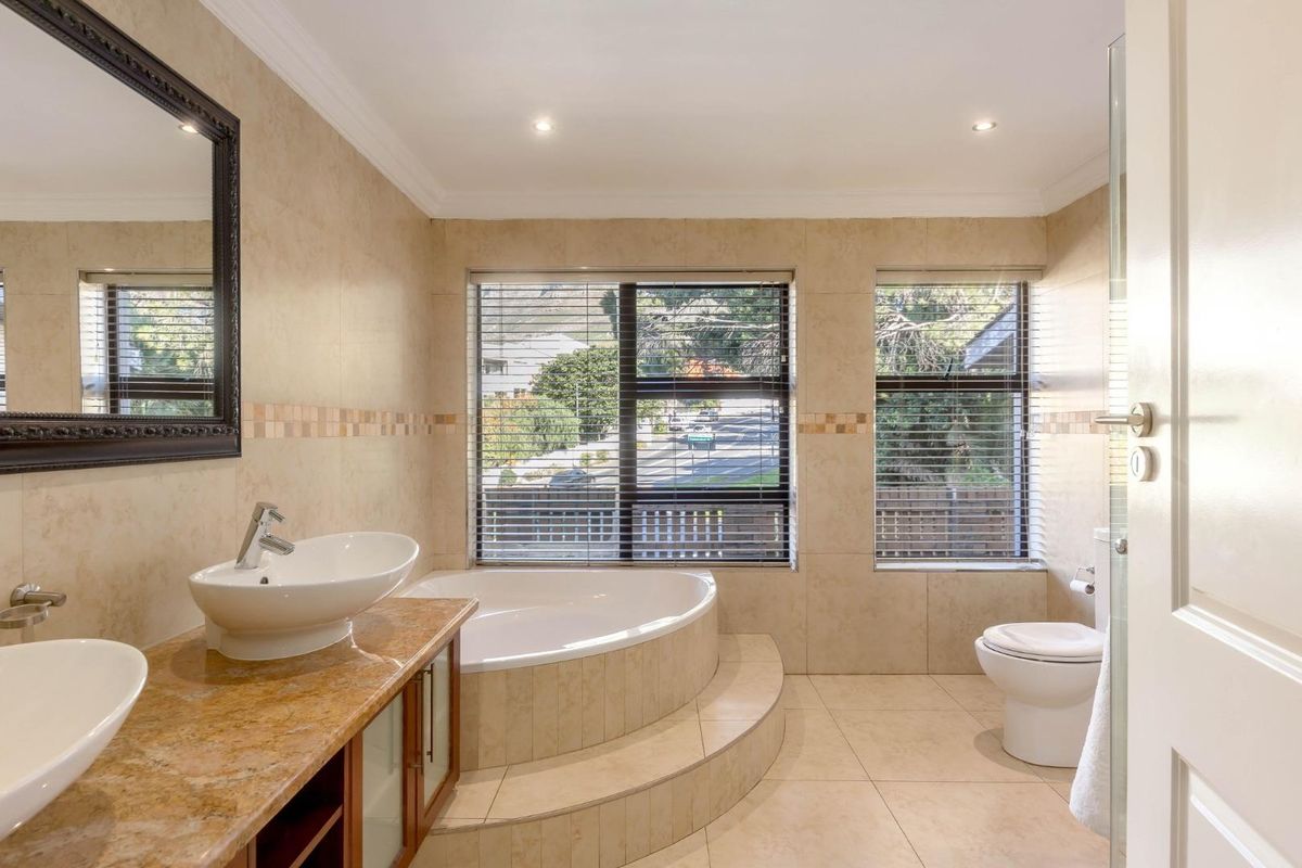 A well-appointed bathroom featuring a dual vanity with stone countertop, vessel sinks, and a raised corner bathtub set against large windows.