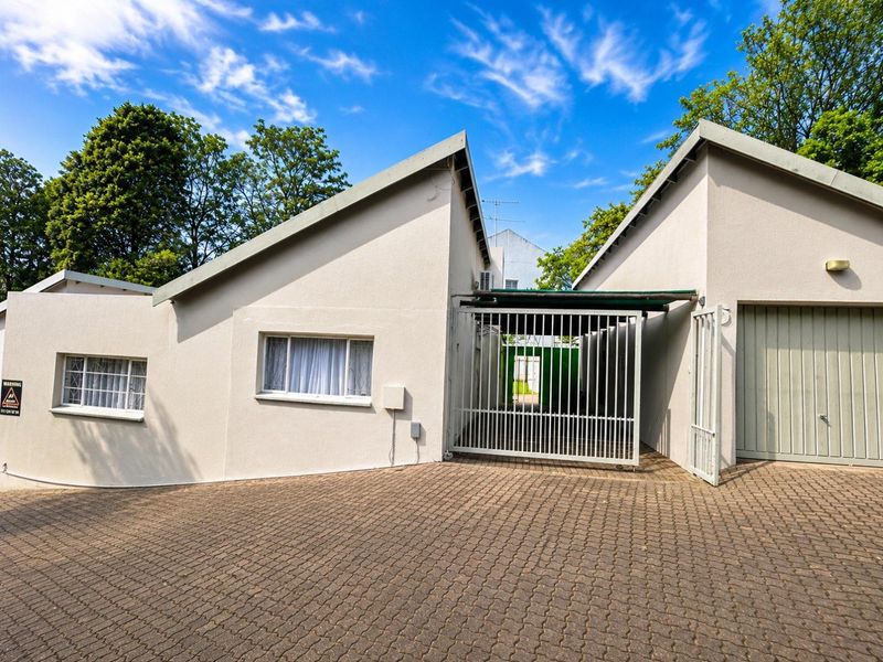 Front exterior view of the apartment featuring a paved driveway, secure gated entrance, and garage access.
