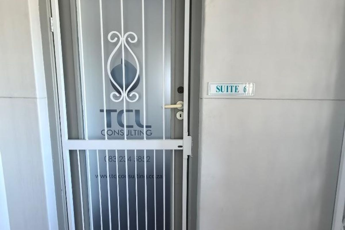 Office suite entrance featuring a white security gate and frosted glass door with professional business signage.