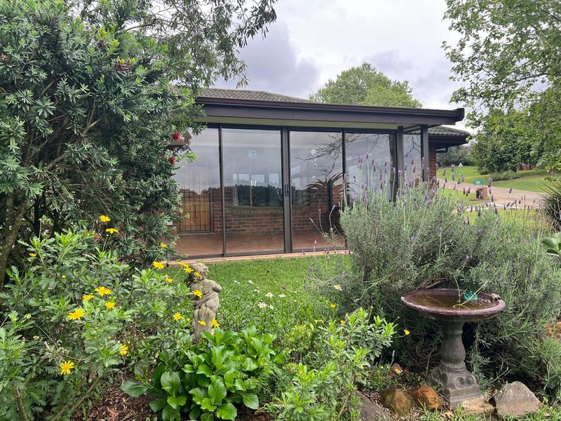A view of the rear exterior of the townhouse, featuring a covered patio area with large sliding glass doors and established garden landscaping.