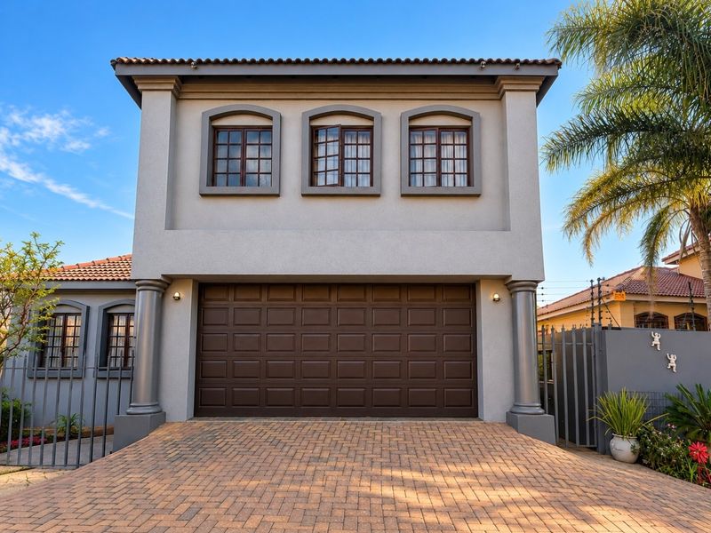 A well-maintained double-storey home exterior featuring a paved driveway, a secure double garage, and classic architectural detailing with multi-pane windows.